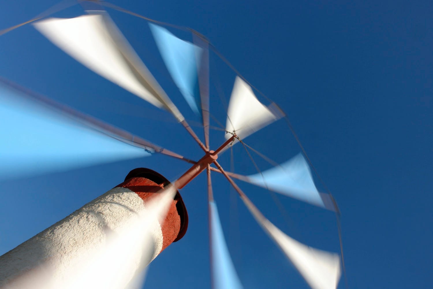 Les ailes d’un moulin tournent dans un ciel bleu, en léger flou de mouvement.